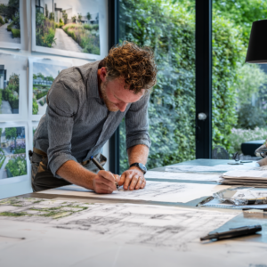 Tuinontwerper werkt aan handgetekend tuinontwerp aan de tekentafel bij Plan de Jardin